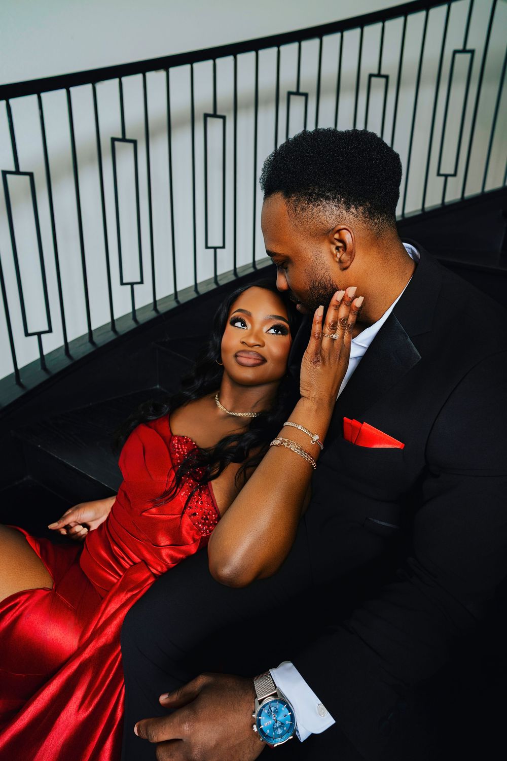 Romantic couple in formal attire share intimate moments in a stylish photoshoot against dark background.
