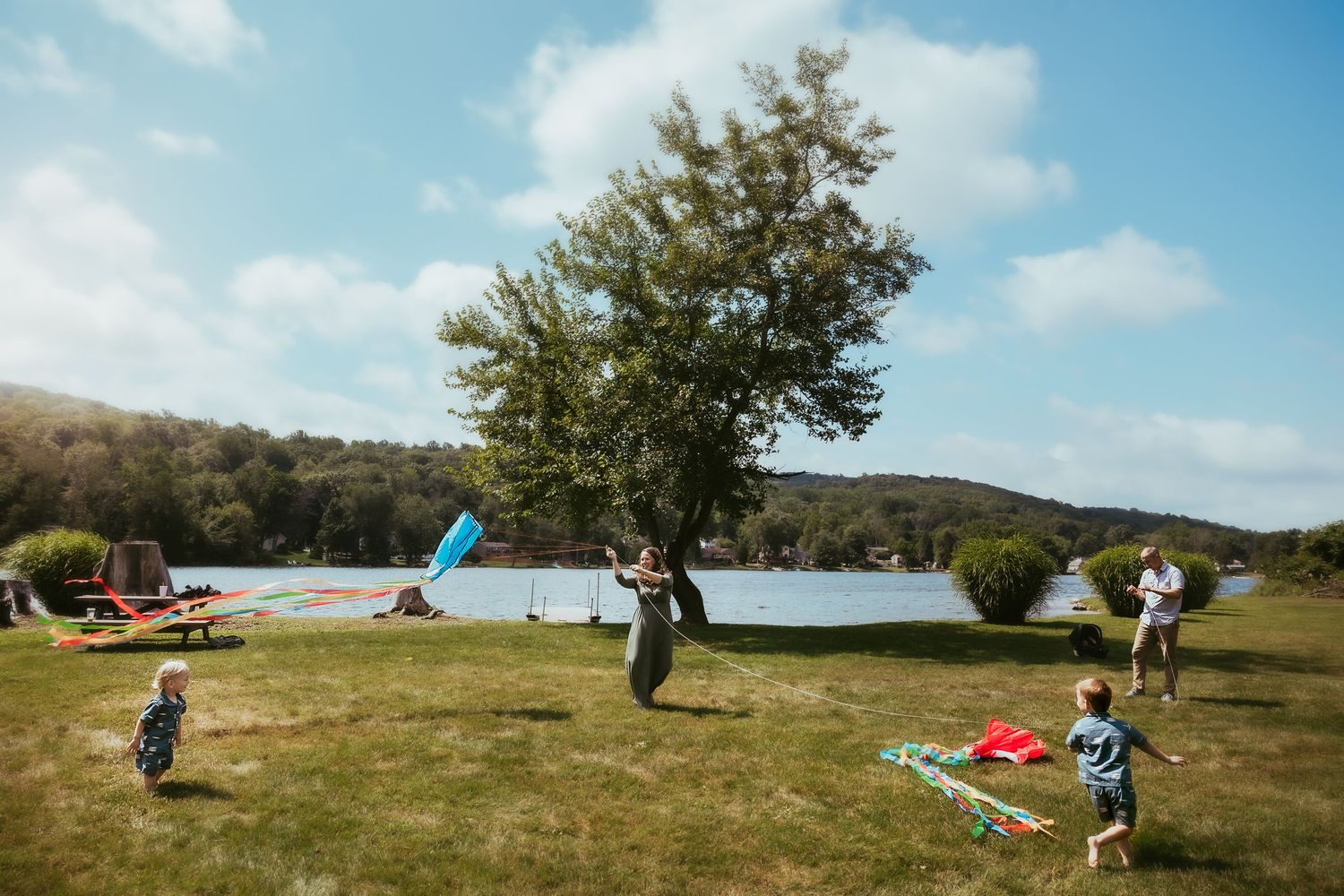 A sequence of kitesurfing action shots showing a person launching and flying a blue kite on a grassy coastal area.
