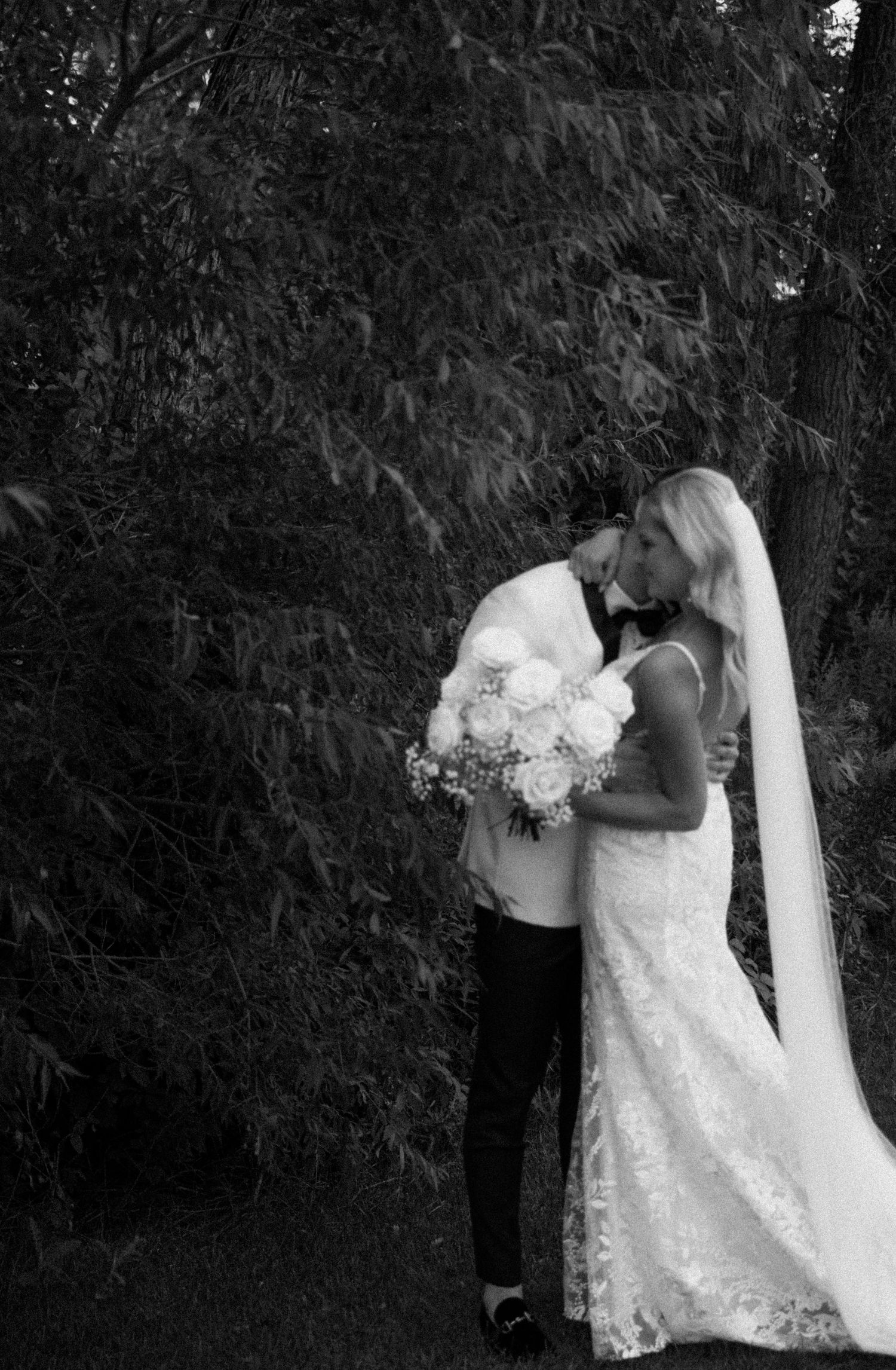 Elegant black and white wedding portrait against dark foliage.
