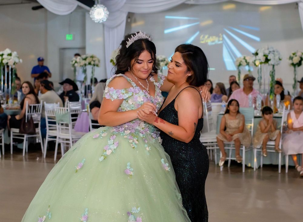 An emotional moment shared during a quinceañera celebration in a decorated reception hall.