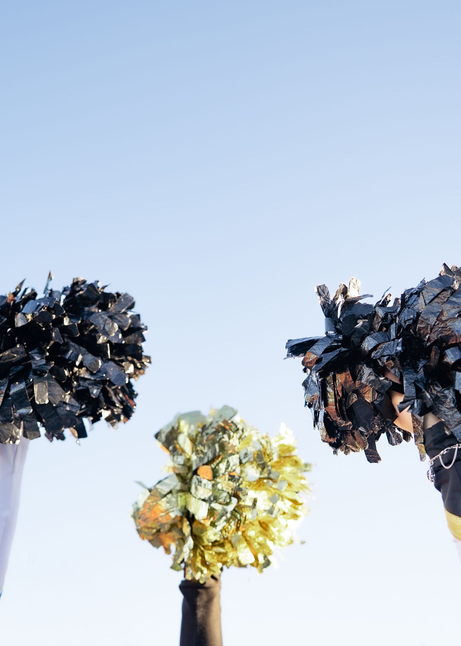 Cheerleaders tossing pom-poms in the air during outdoor group portrait