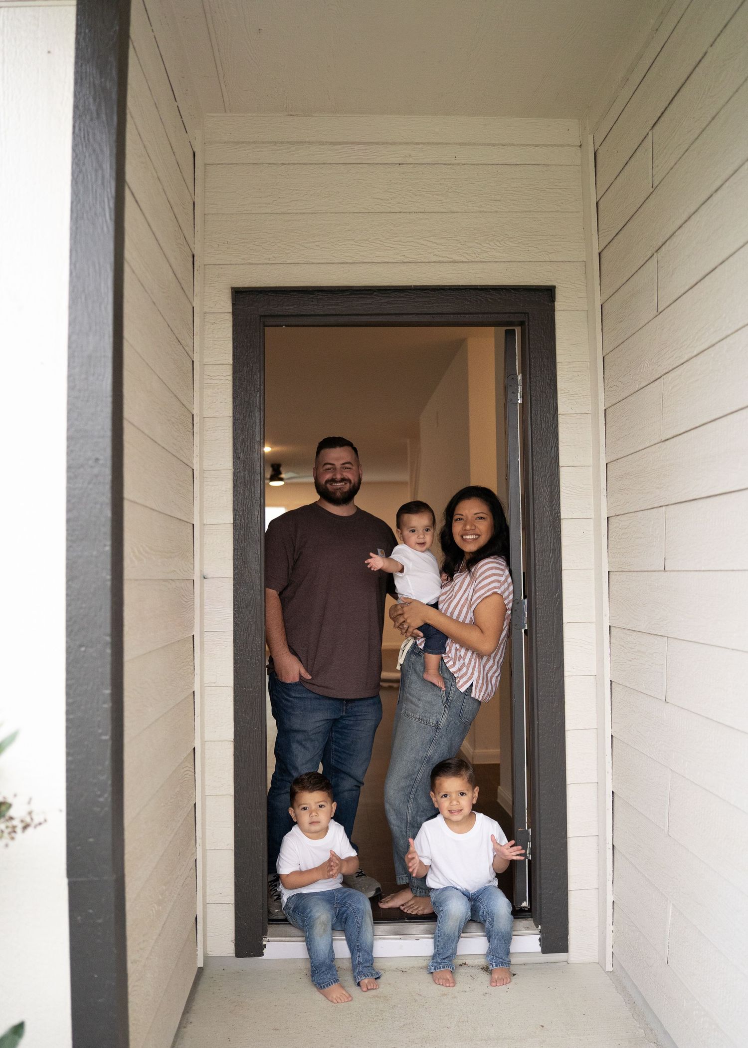 The Emerson Family of five posing in their empty new home, smiling and exploring their new space together