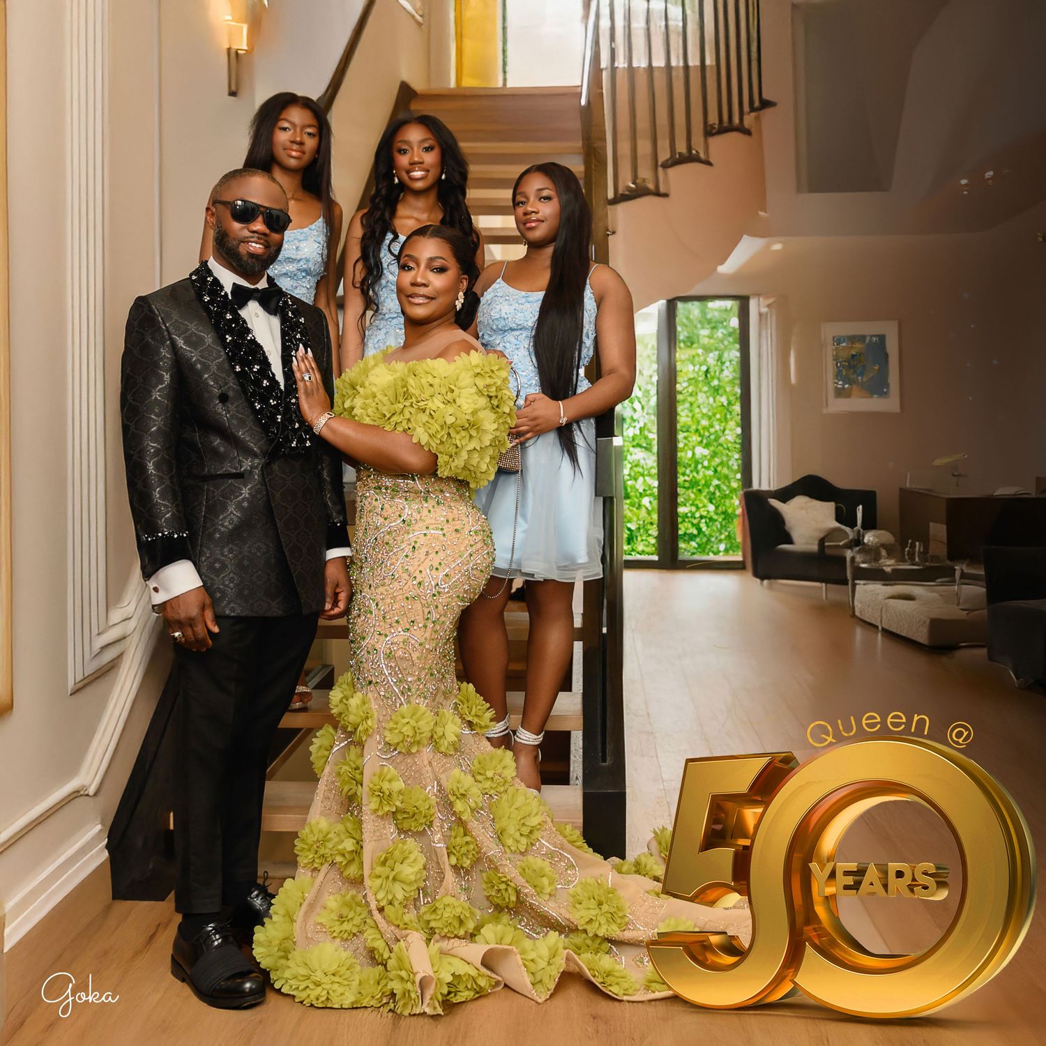 Elegant couple poses in formal attire with yellow and gold accents against a white staircase and decorative gold rings.