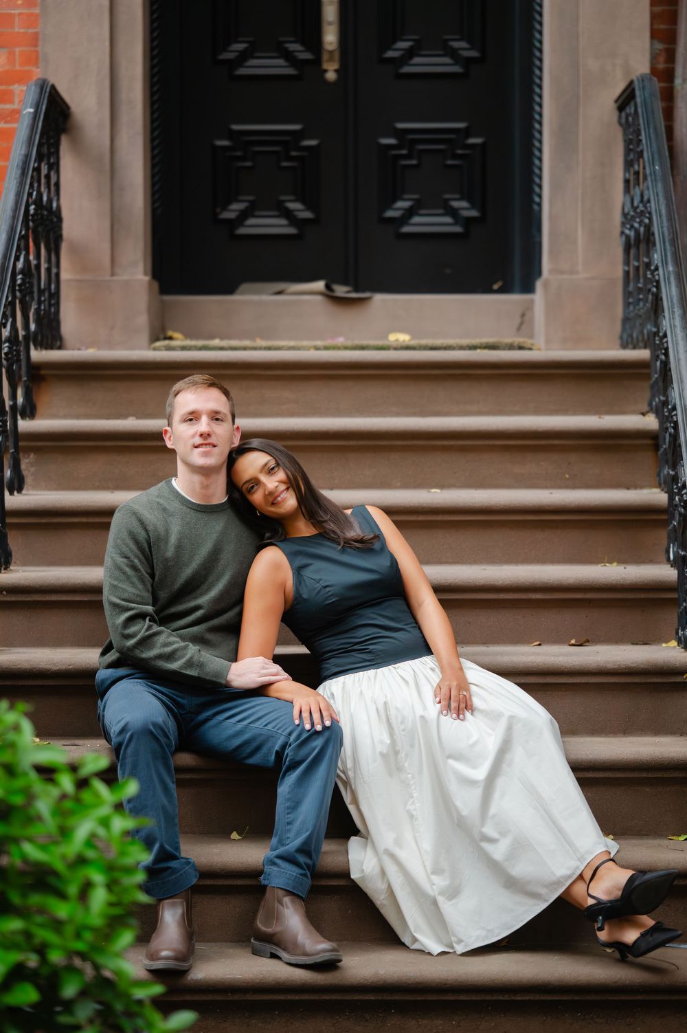 Couple sitting and relaxing on brownstone steps in an urban neighborhood.