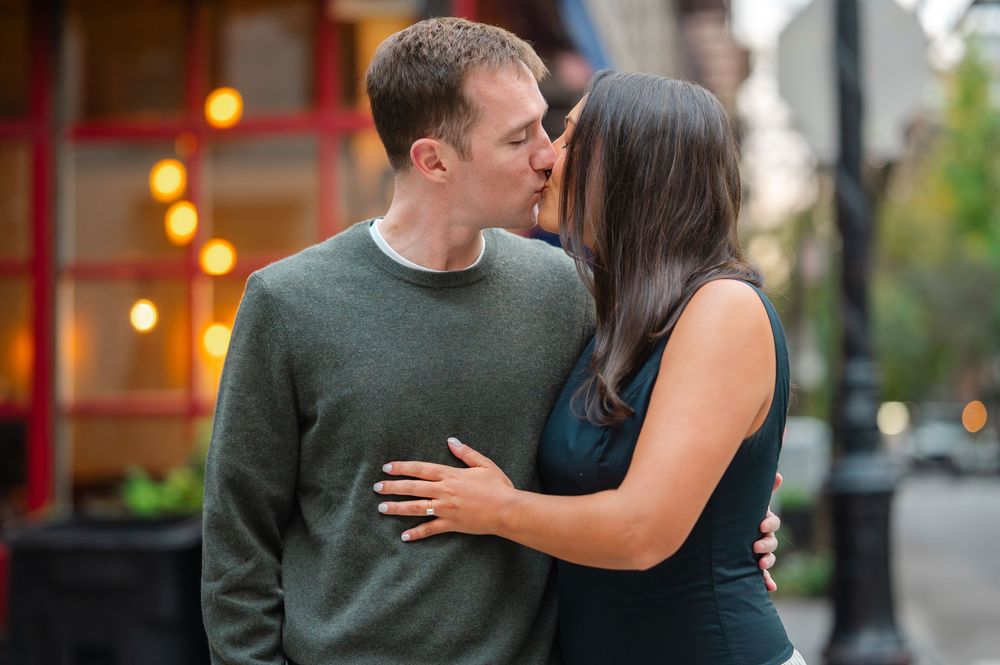 A couple sits close together on outdoor steps during an intimate engagement photo session.