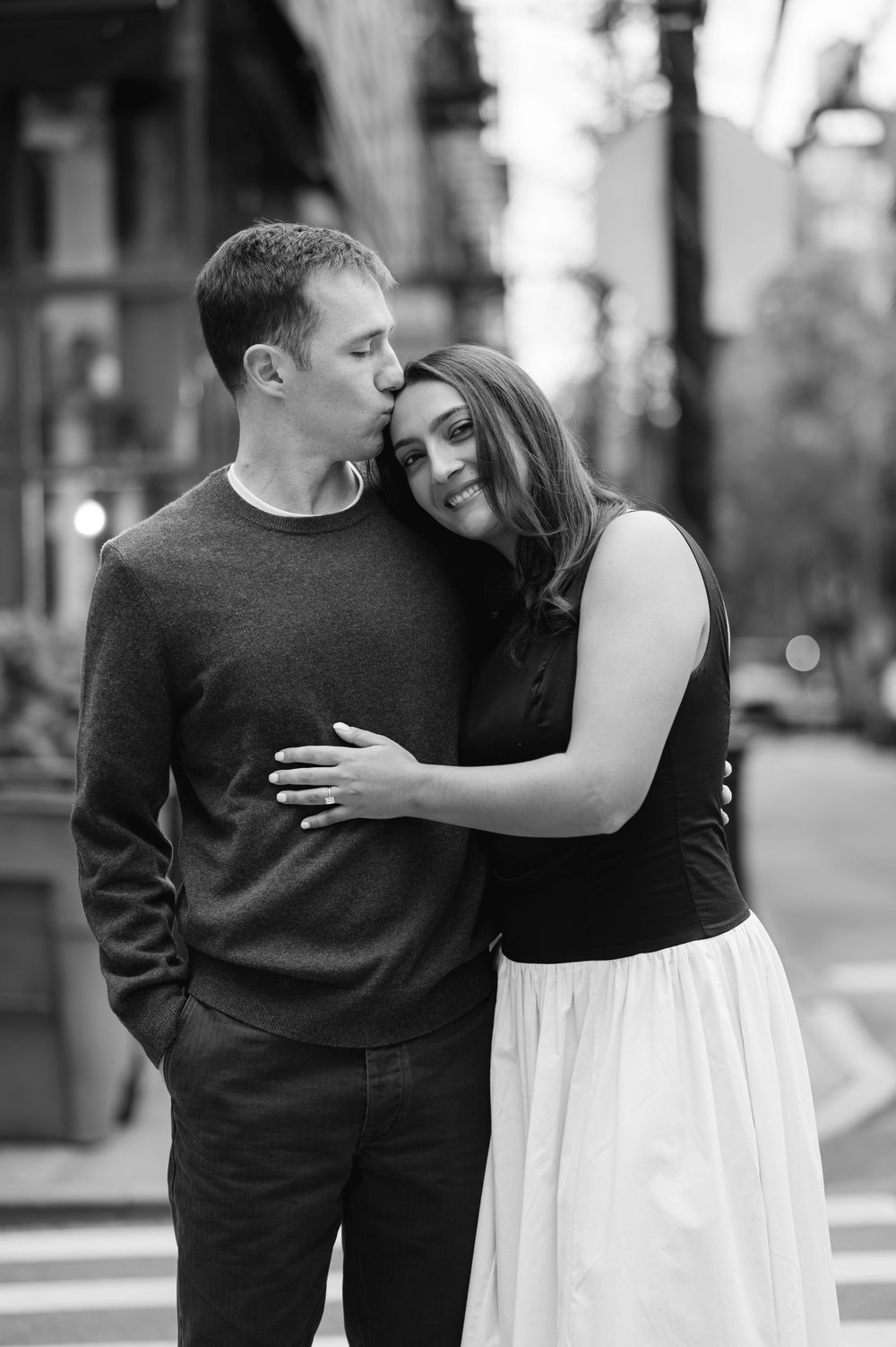 Romantic black and white portrait of a couple embracing on a city street.