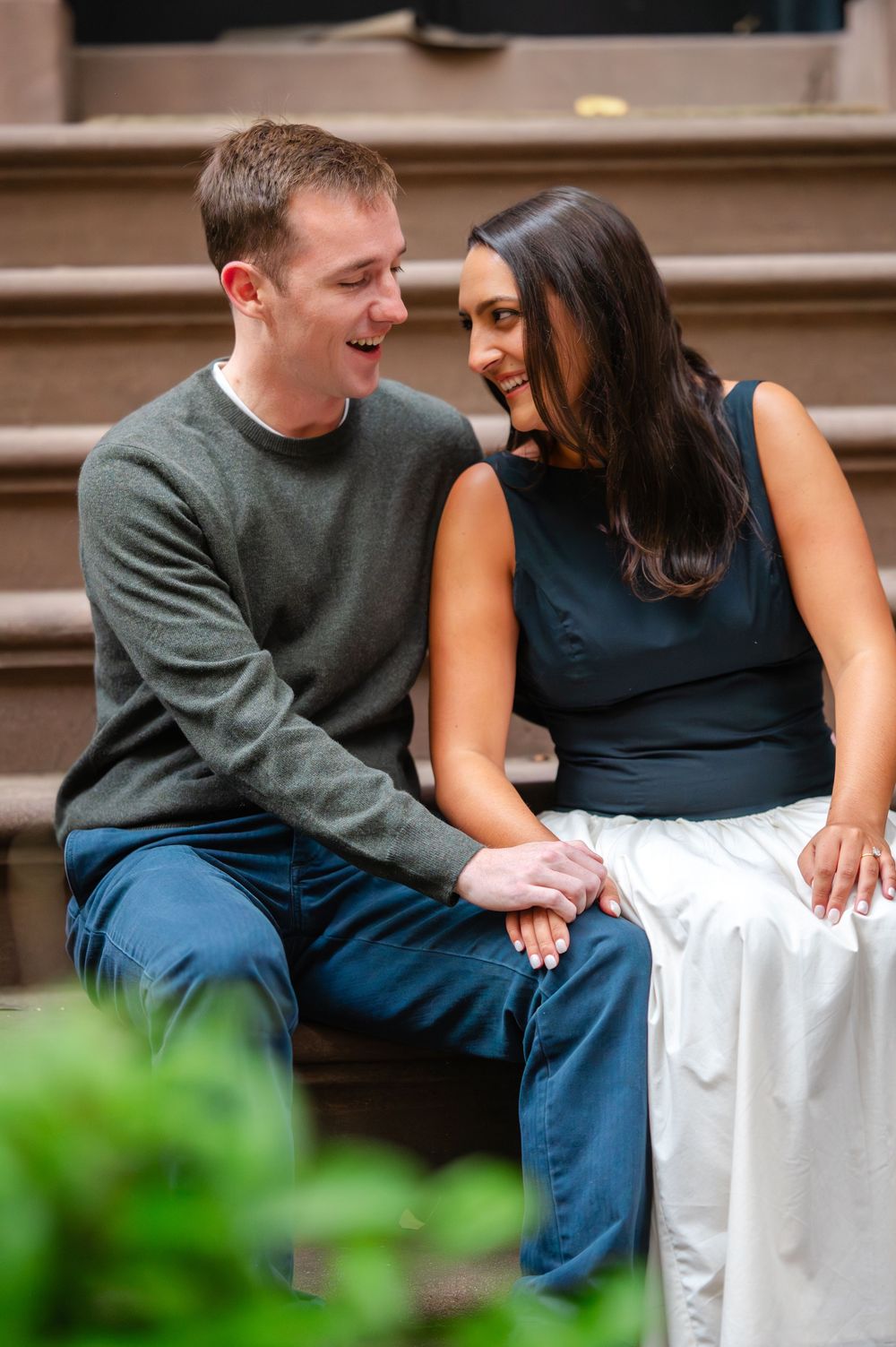 A couple shares an intimate moment while sitting on urban brownstone steps.