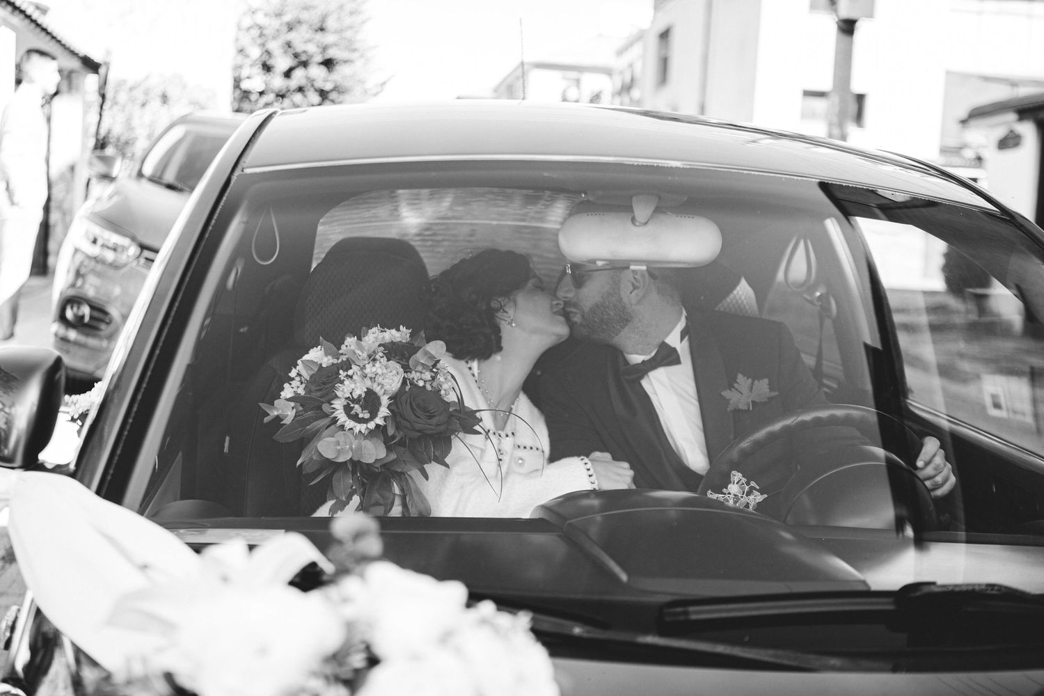 Newlyweds share a romantic kiss inside a decorated car after their wedding ceremony.