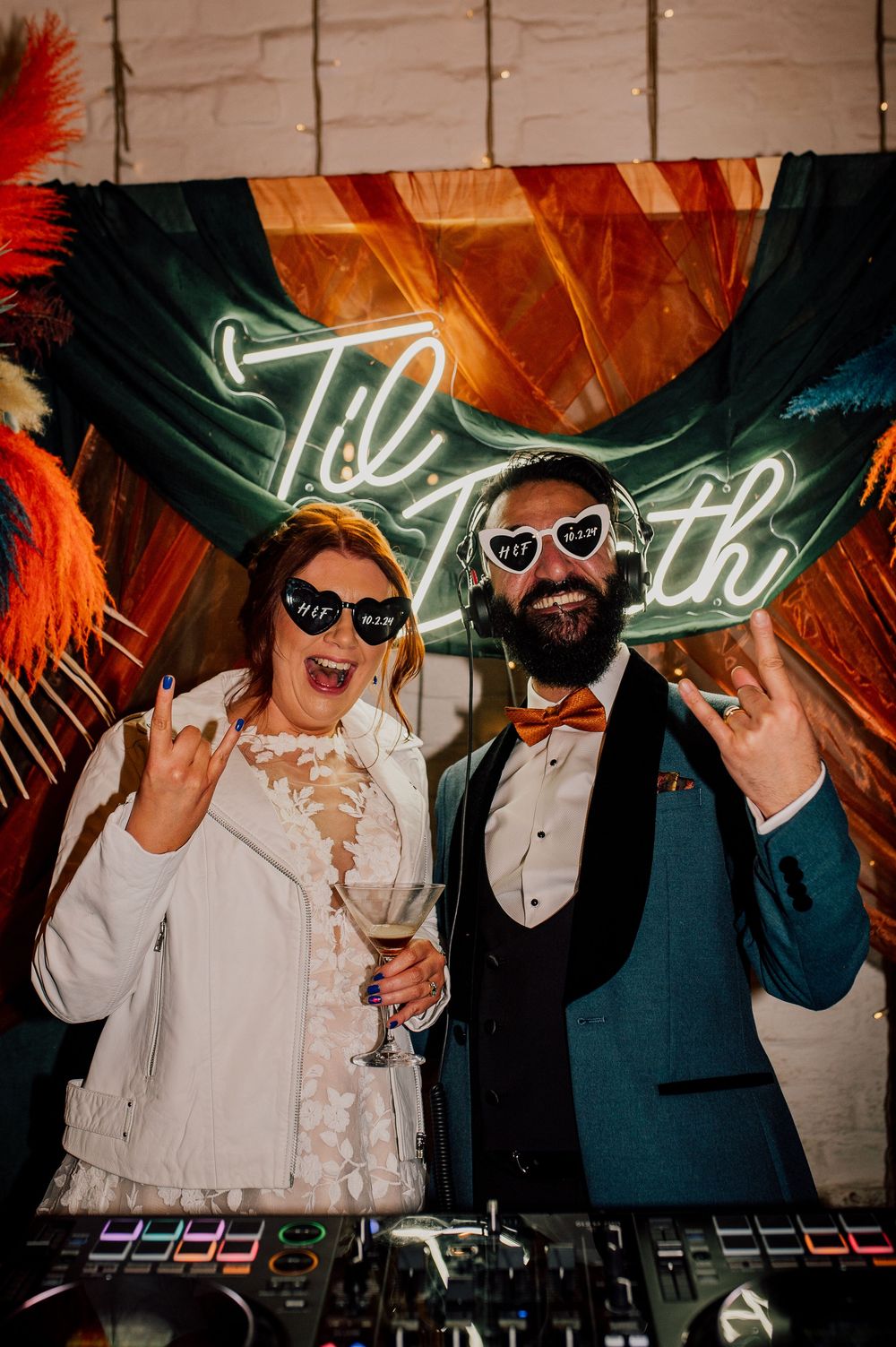 Wedding party guests wearing sunglasses dance and pose under neon lighting at a reception celebration. Worcestershire Wedding photographer.