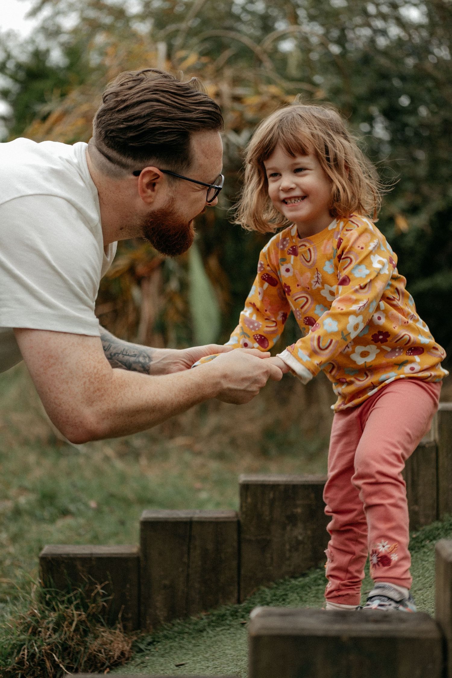 A father holding his autistic daughters hand as she prepares to jump, Both are smiling at each other