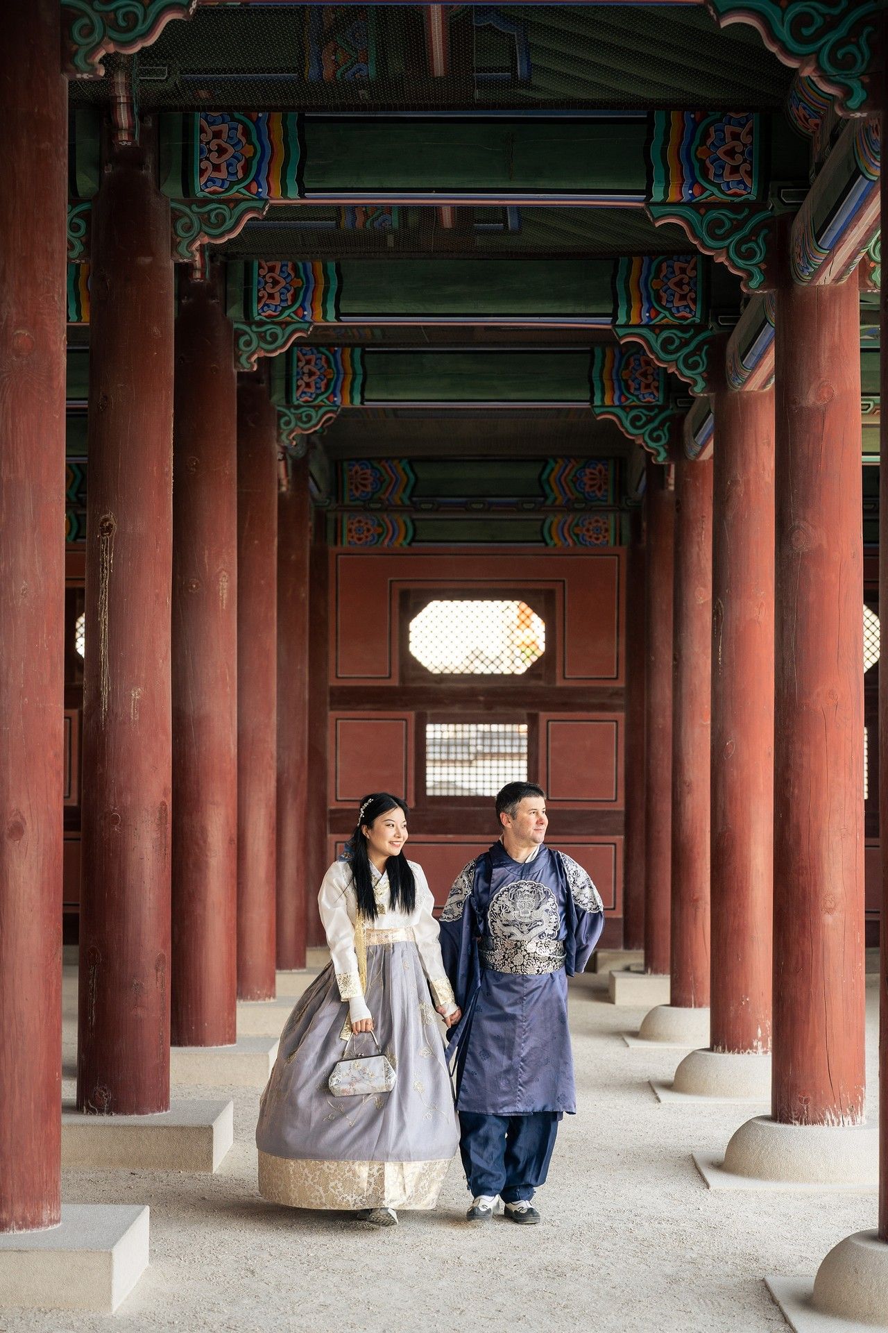 Traditional Korean palace corridor with red wooden pillars and stone benches at Gyeongbokgung Palace in Seoul.