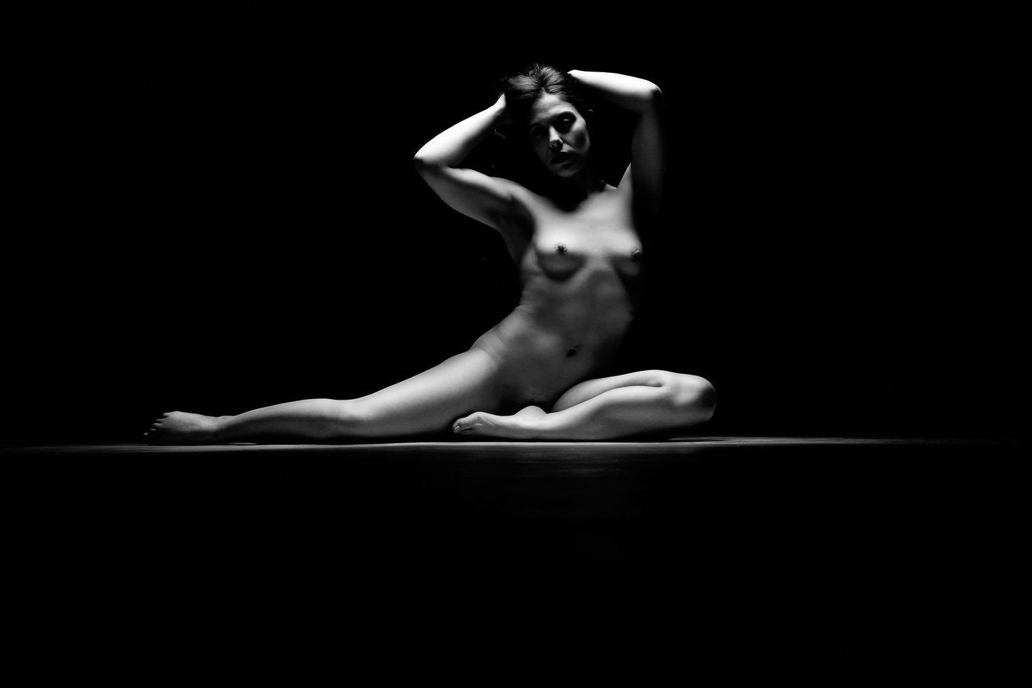 David G Holt Photography - Black and white artistic boudoir portrait showing a figure reclining on white bedding in soft natural light.