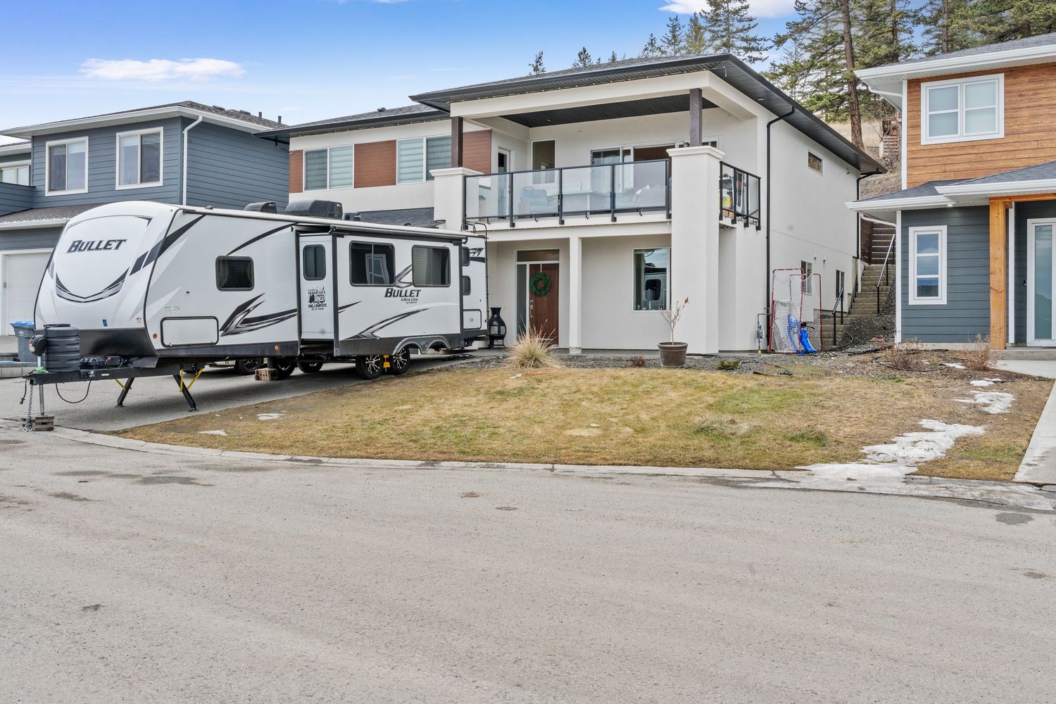 Exterior view of modern homes and RVs parked in a residential neighborhood with mountains in the background.
