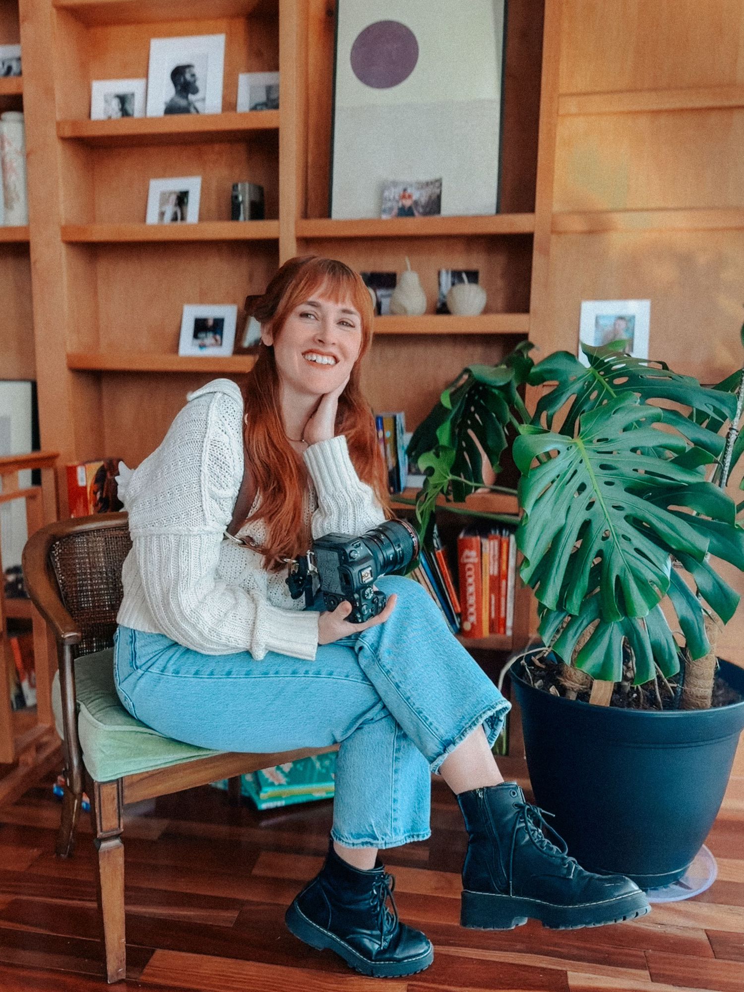 A photographer wearing a blue button-down shirt takes a mirror selfie with a professional camera.