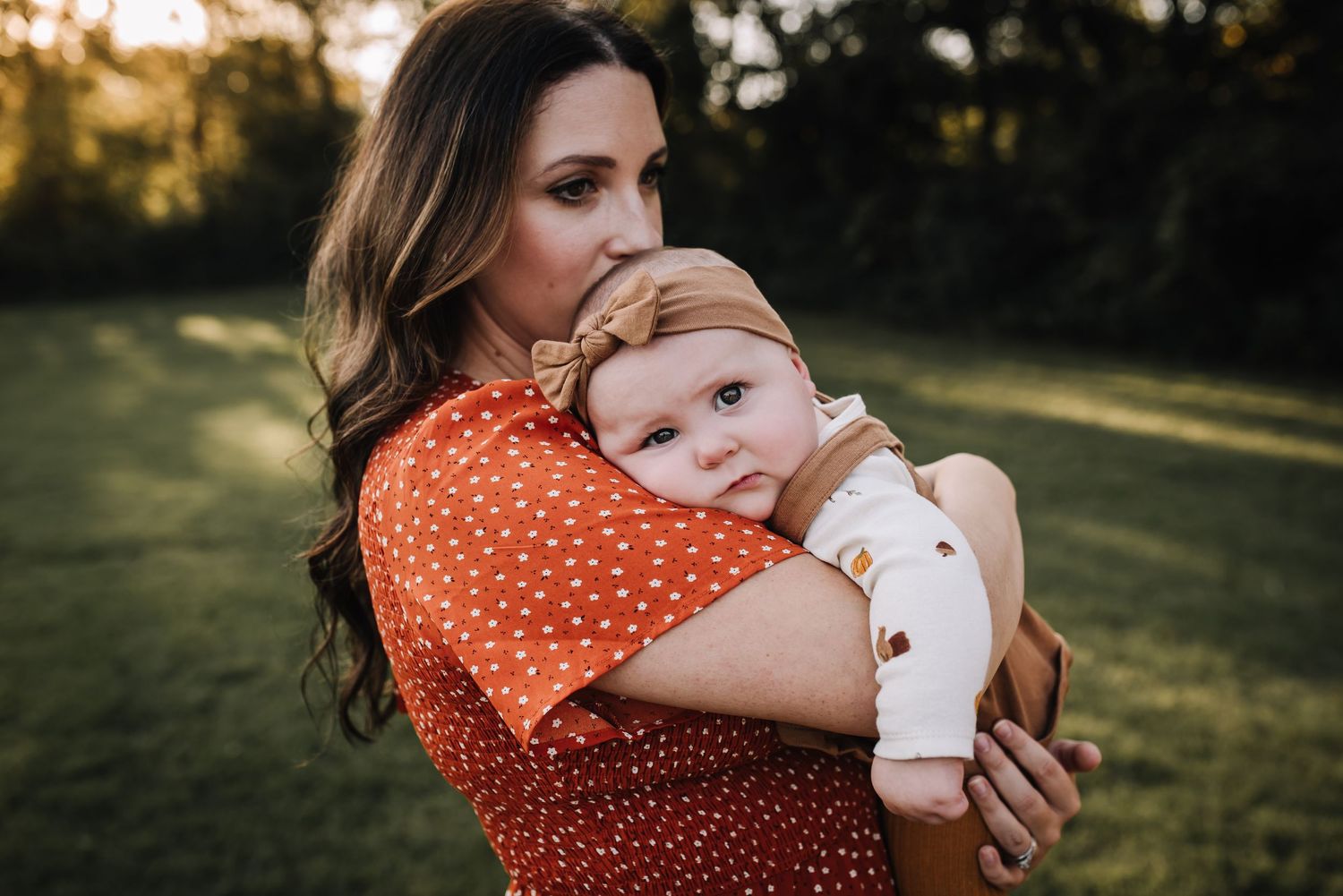 Baby in brown sweater and white blanket lying on grass during golden hour outdoor photoshoot. Family photographer in Middle Tennessee captur