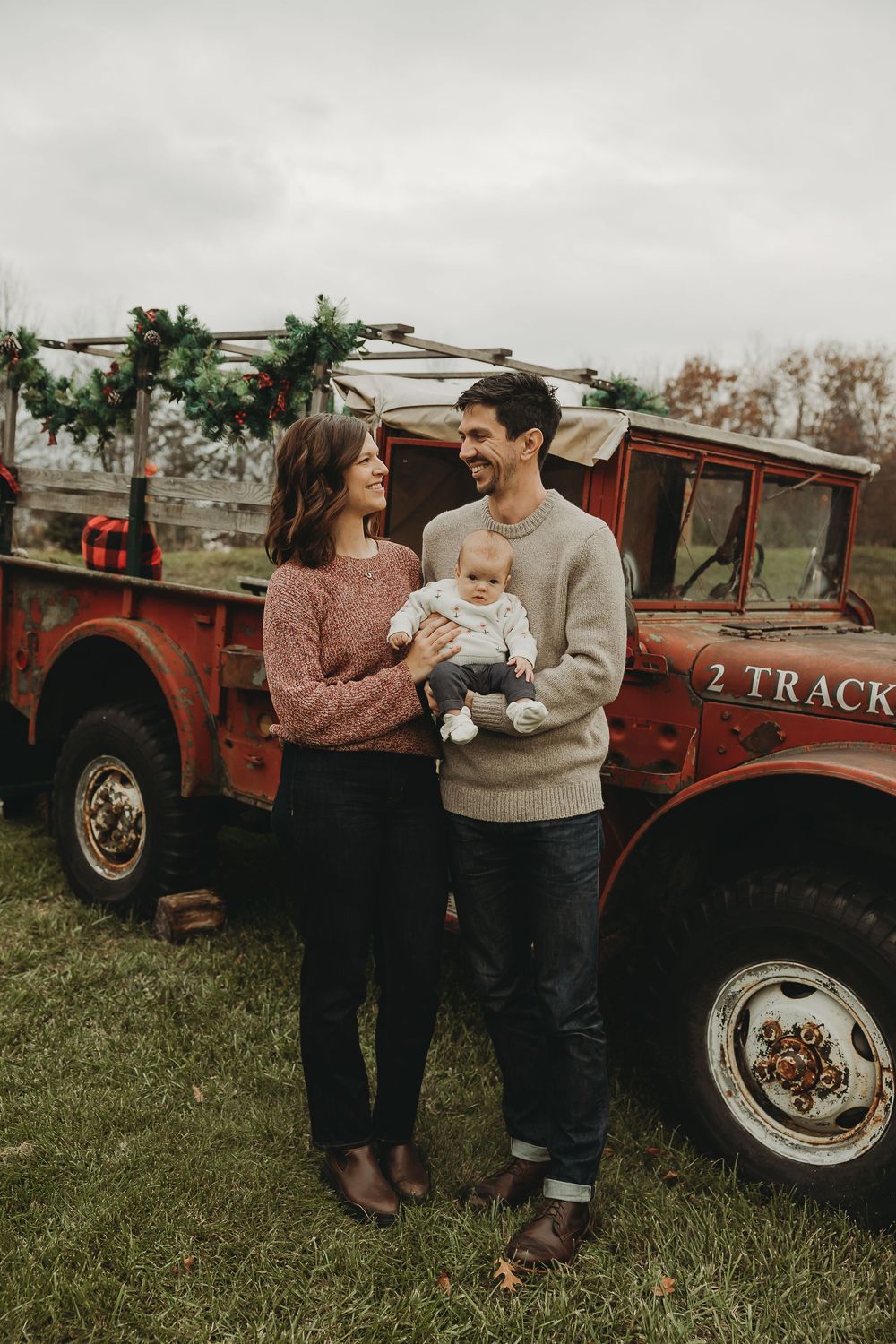 Couple sharing coffee and intimate moments by vintage red truck in rustic outdoor setting.