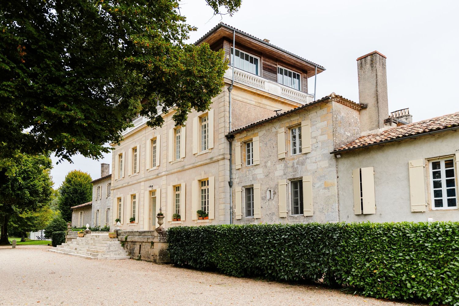 Elegant French chateau with cream stone walls, manicured hedges and classic architectural details in countryside setting.