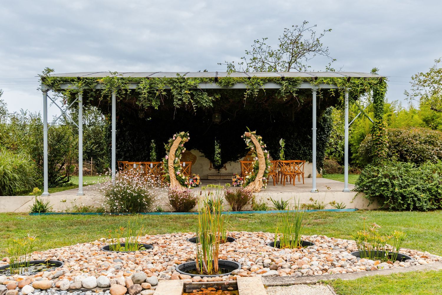 Giraffes graze in an open enclosure at a modern zoo facility with lush greenery and viewing platforms.
