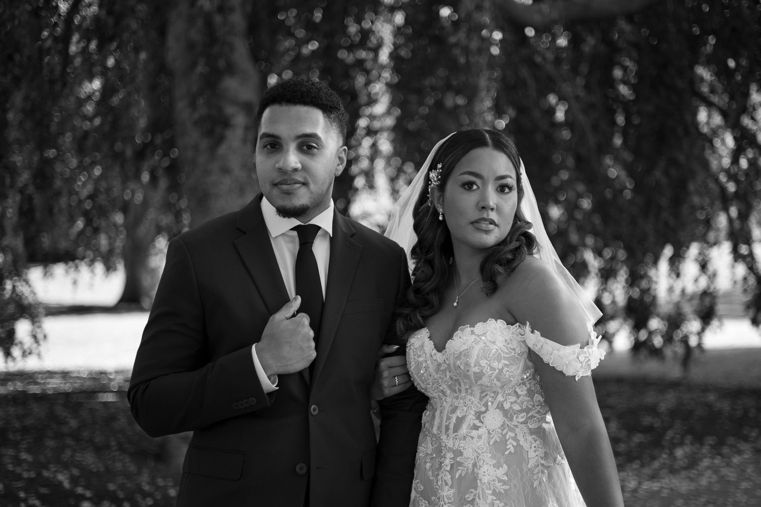 A black and white wedding photo showing a romantic moment between a couple in formal wedding attire.