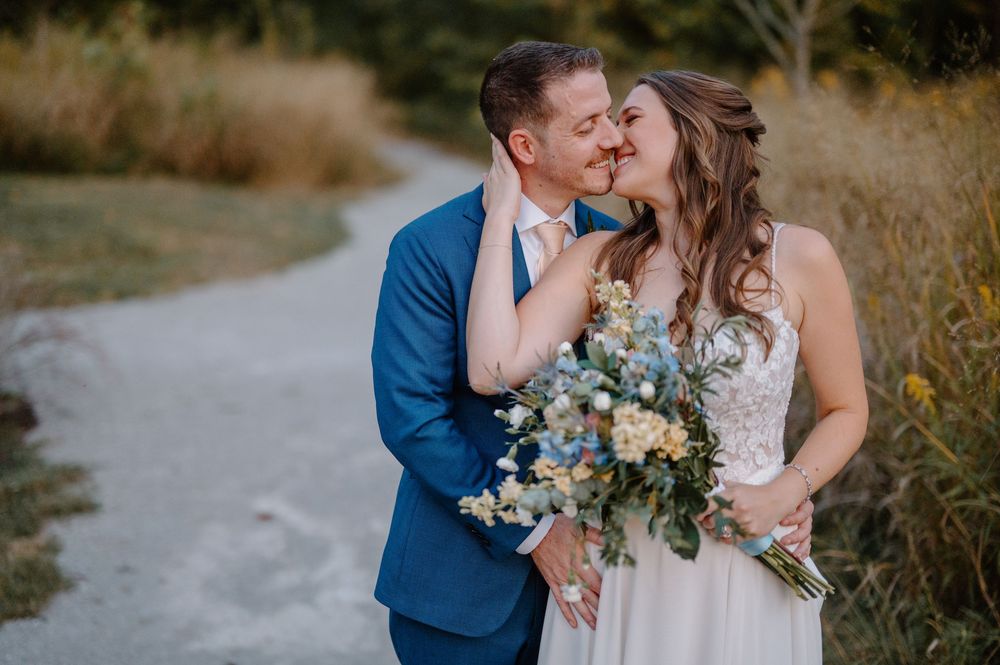 Newlywed couple shares romantic kisses in a rustic outdoor setting with golden light and natural scenery at Cincinnati Nature Center