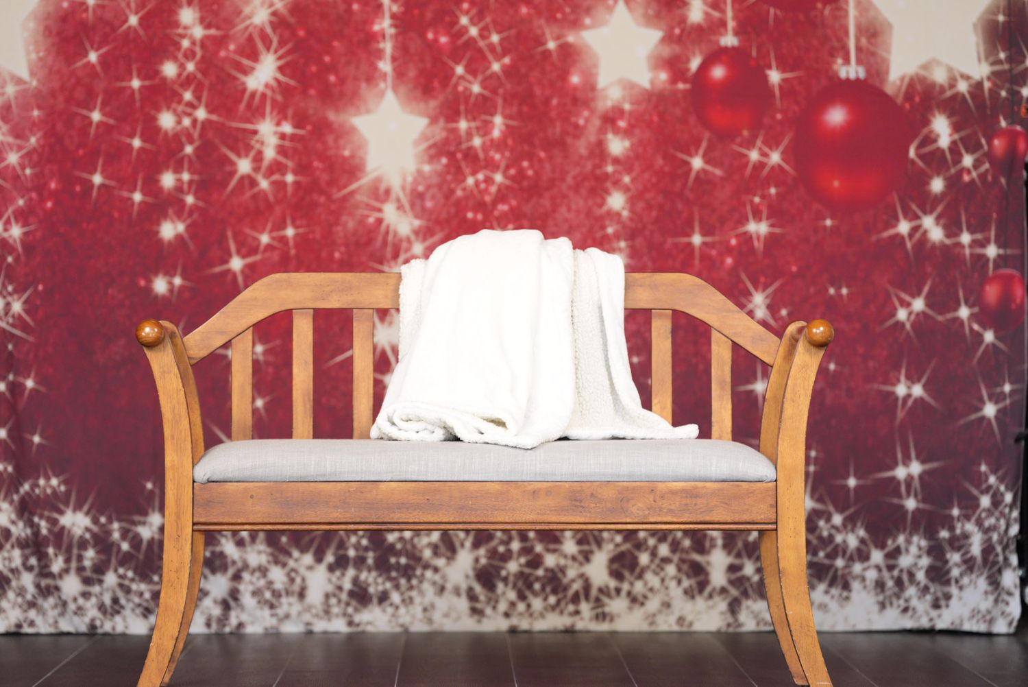 Wooden bed frame with white bedding against a festive red background with sparkling star effects.