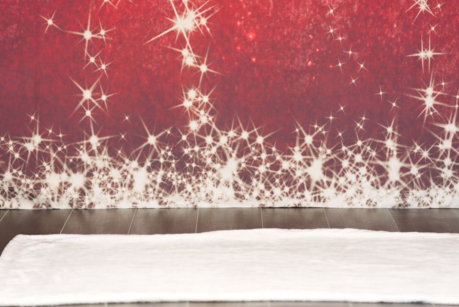 White sparkles and stars glitter against a deep red background with a snowy surface below.