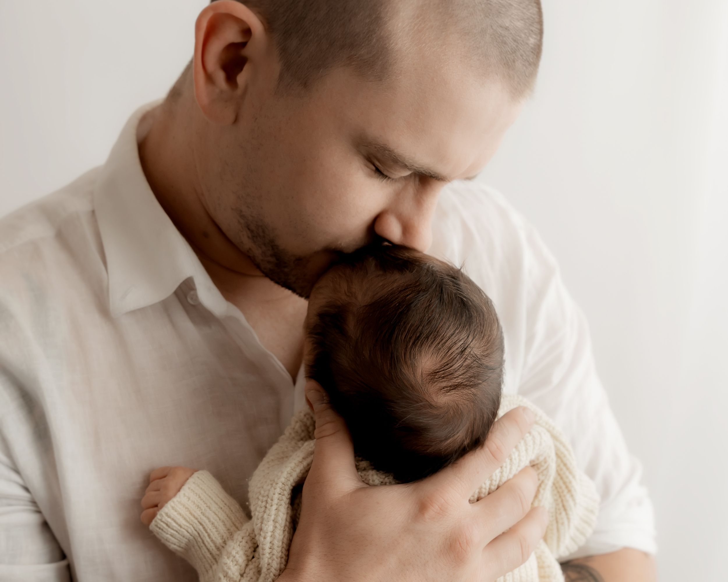 Father kissing newborn baby during newborn photos