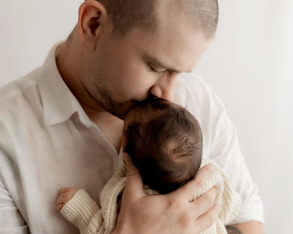 Father kissing newborn baby during newborn photos