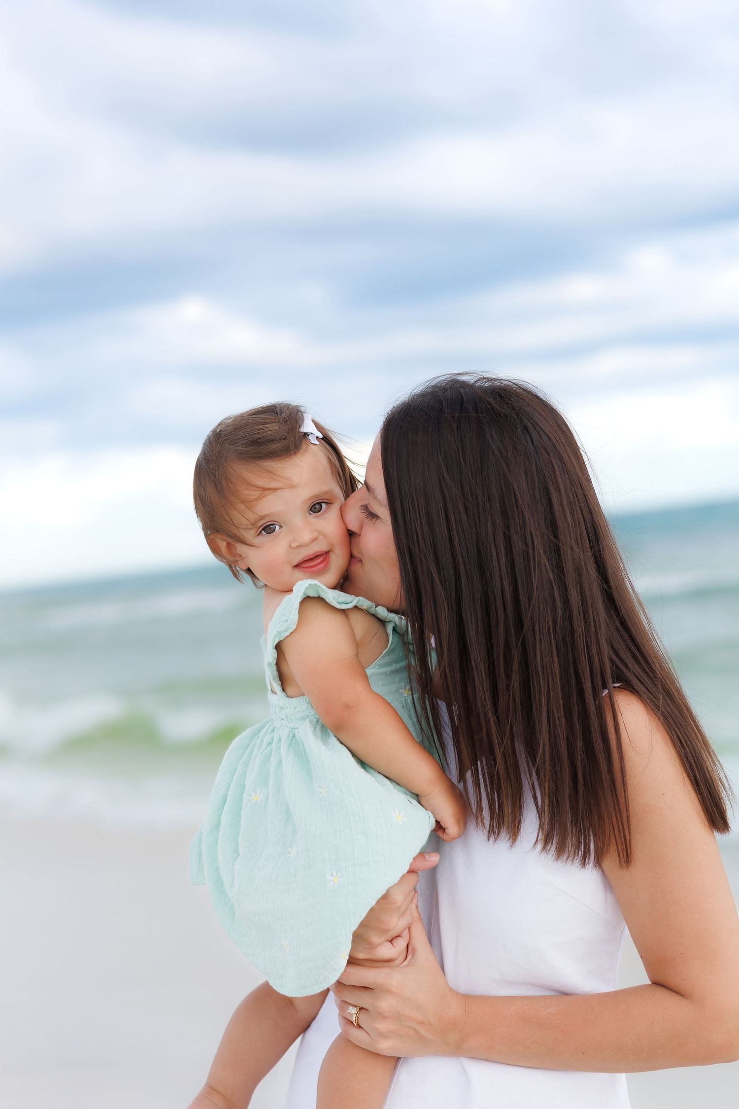 Mother kissing her toddler daughter during a relaxed beach family photo session in Destin, Florida