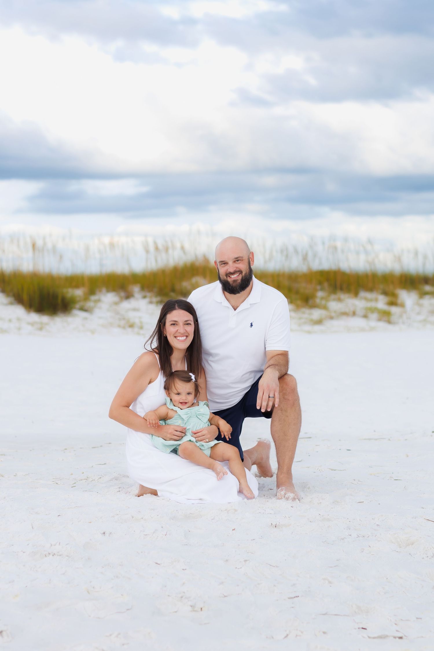 Family sitting together on the beach during a calm, guided family photo session in Destin, Florida.