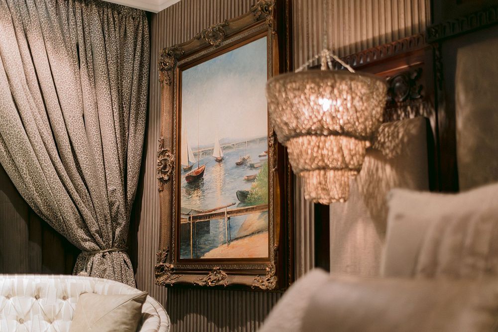 Luxurious bedroom detail with gold-framed sailboat painting and capiz shell chandelier.