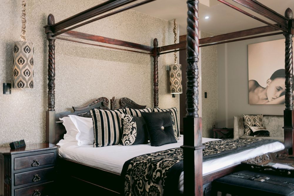 Luxurious four-poster bed with black and white bedding in a sophisticated hotel room.