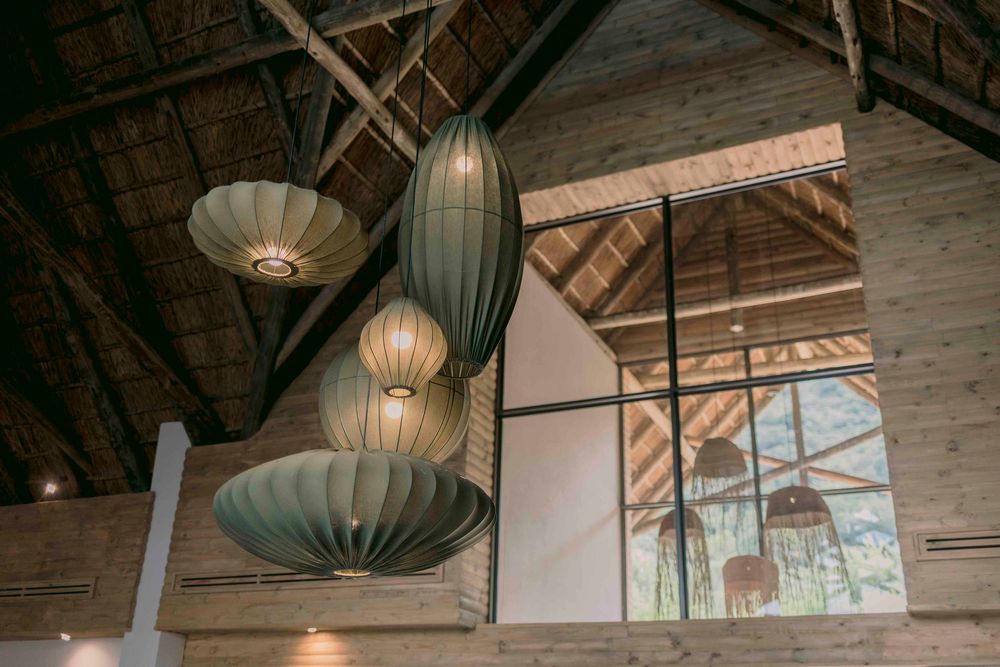 Decorative teal pendant lanterns hanging from a rustic wooden thatched ceiling in a lodge interior.
