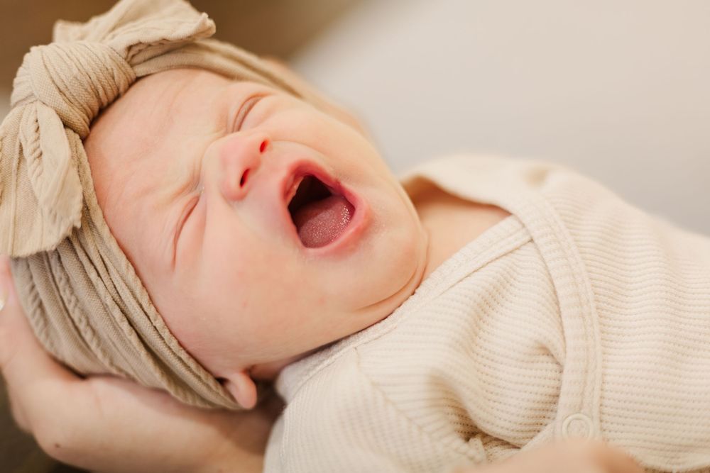 A series of photos showing a yawning baby in a cream-colored sweater, captured in sequence from different angles.