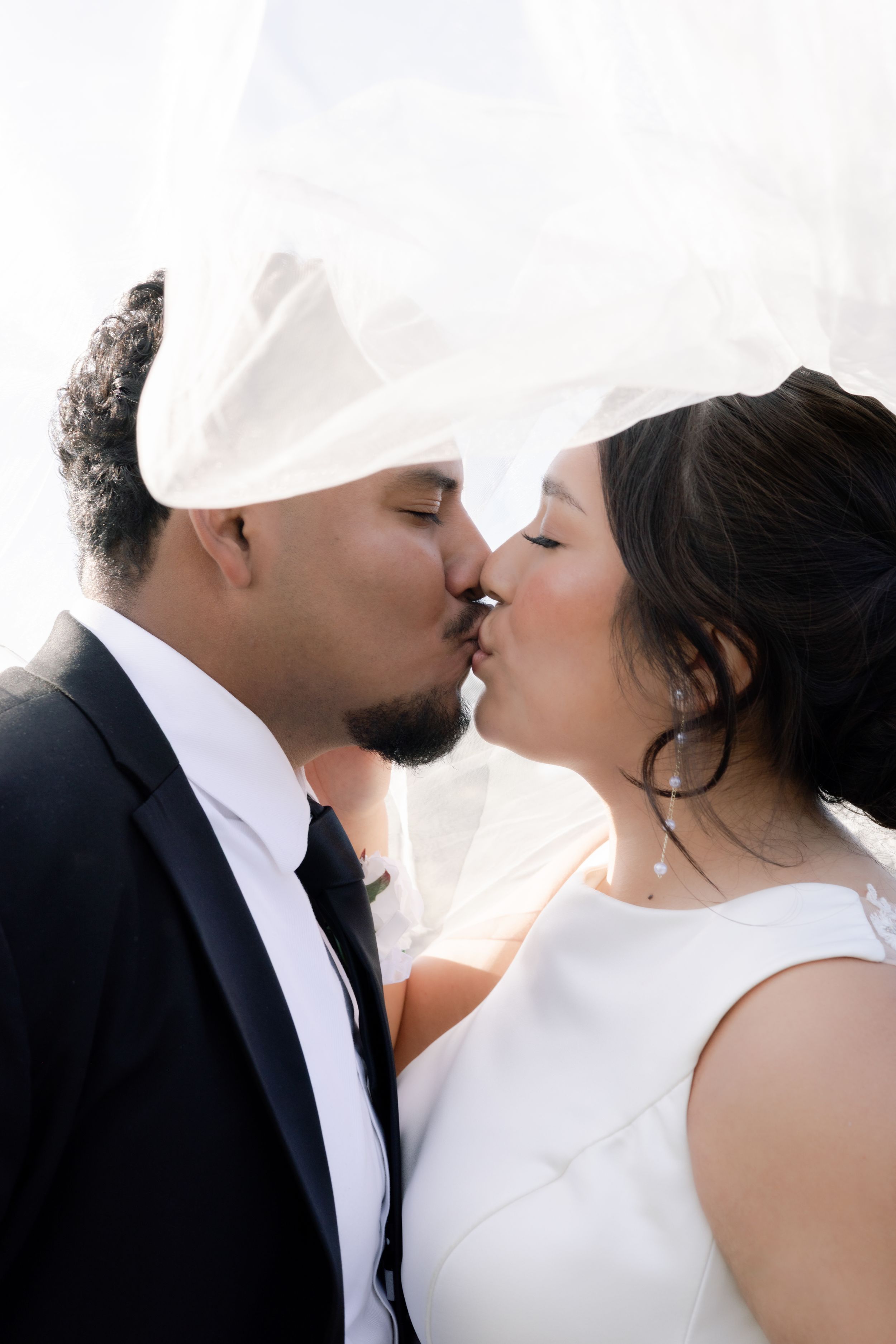 A romantic wedding kiss sequence showing multiple angles of a couple in white attire against a light background.