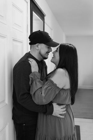 A romantic black and white photo of a couple embracing against a wall, creating an intimate moment.