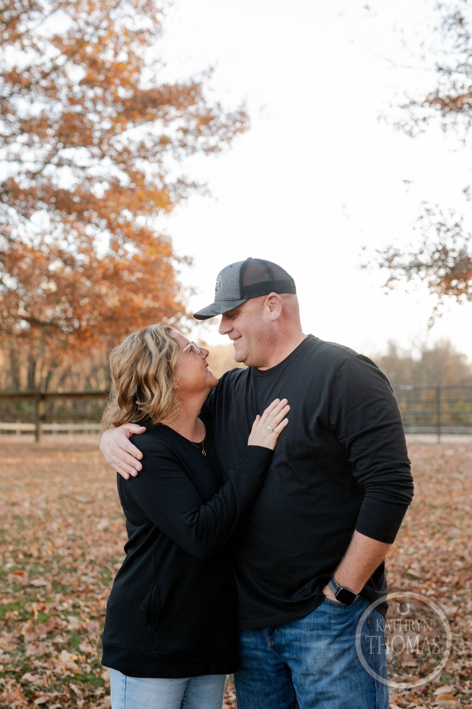 Intimate couple moment captured in autumn park setting with fallen leaves.