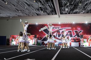 Cheerleaders perform a stunt formation during a competition with red Pepsi Max banners in the background.
