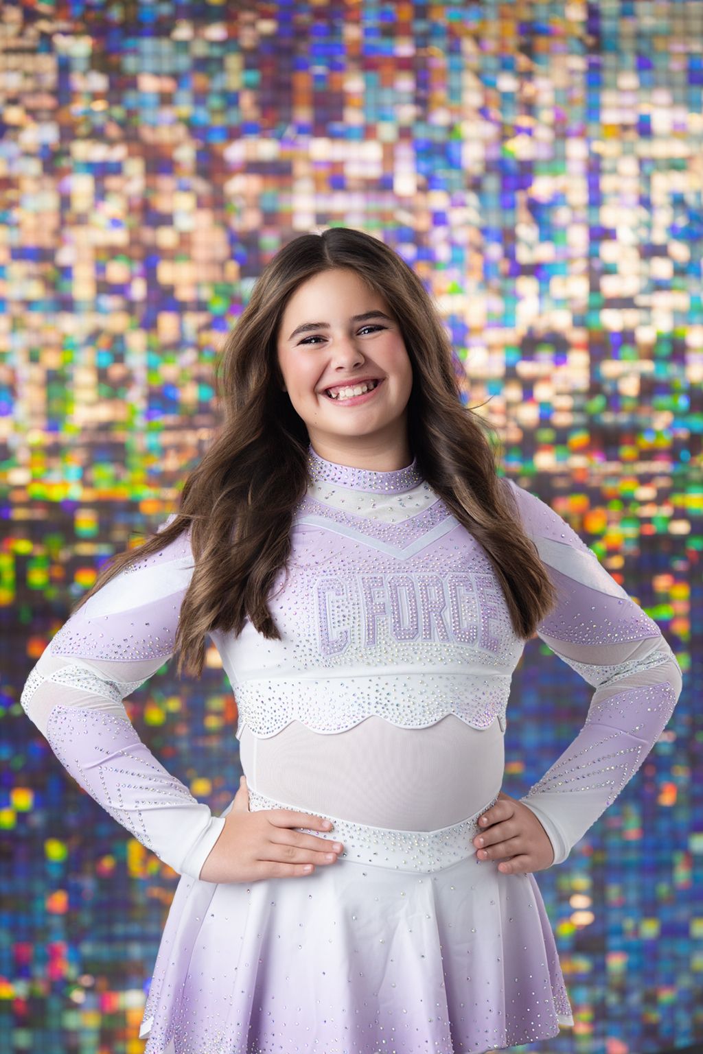 A person wearing a white sparkly dress poses against a colorful holographic background.