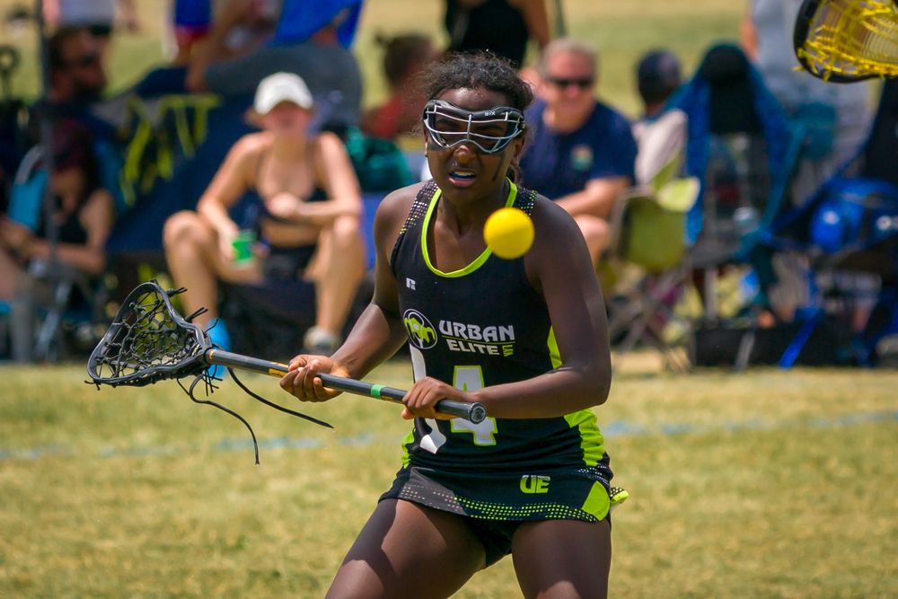 Athletes in yellow uniforms sprint across grass field during competitive sports match.