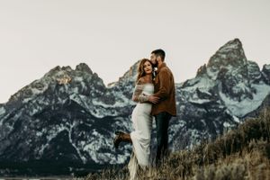 A couple shares a tender moment against the majestic backdrop of the Grand Tetons mountains.