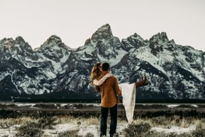 A romantic embrace with the dramatic Teton mountain range creating a stunning winter backdrop.