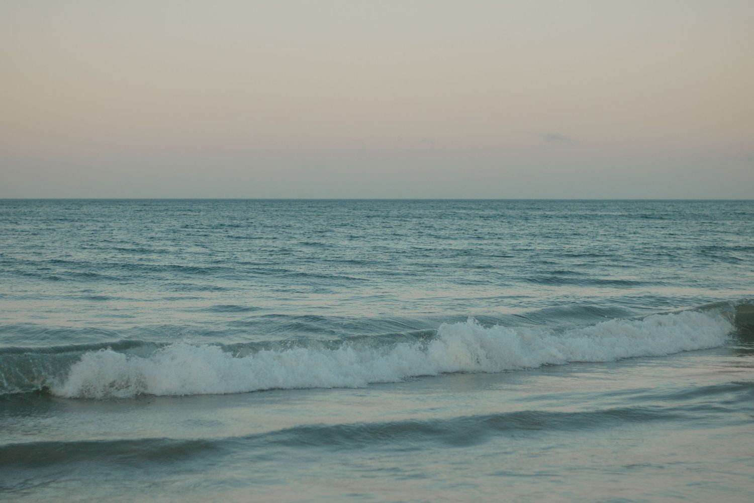 Serene ocean waves rolling against the shoreline at dusk.