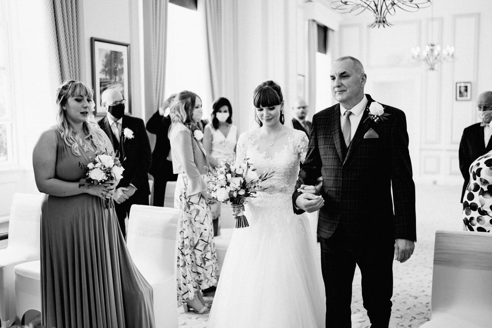 Black and white photo of wedding ceremony with attendees in formal attire.