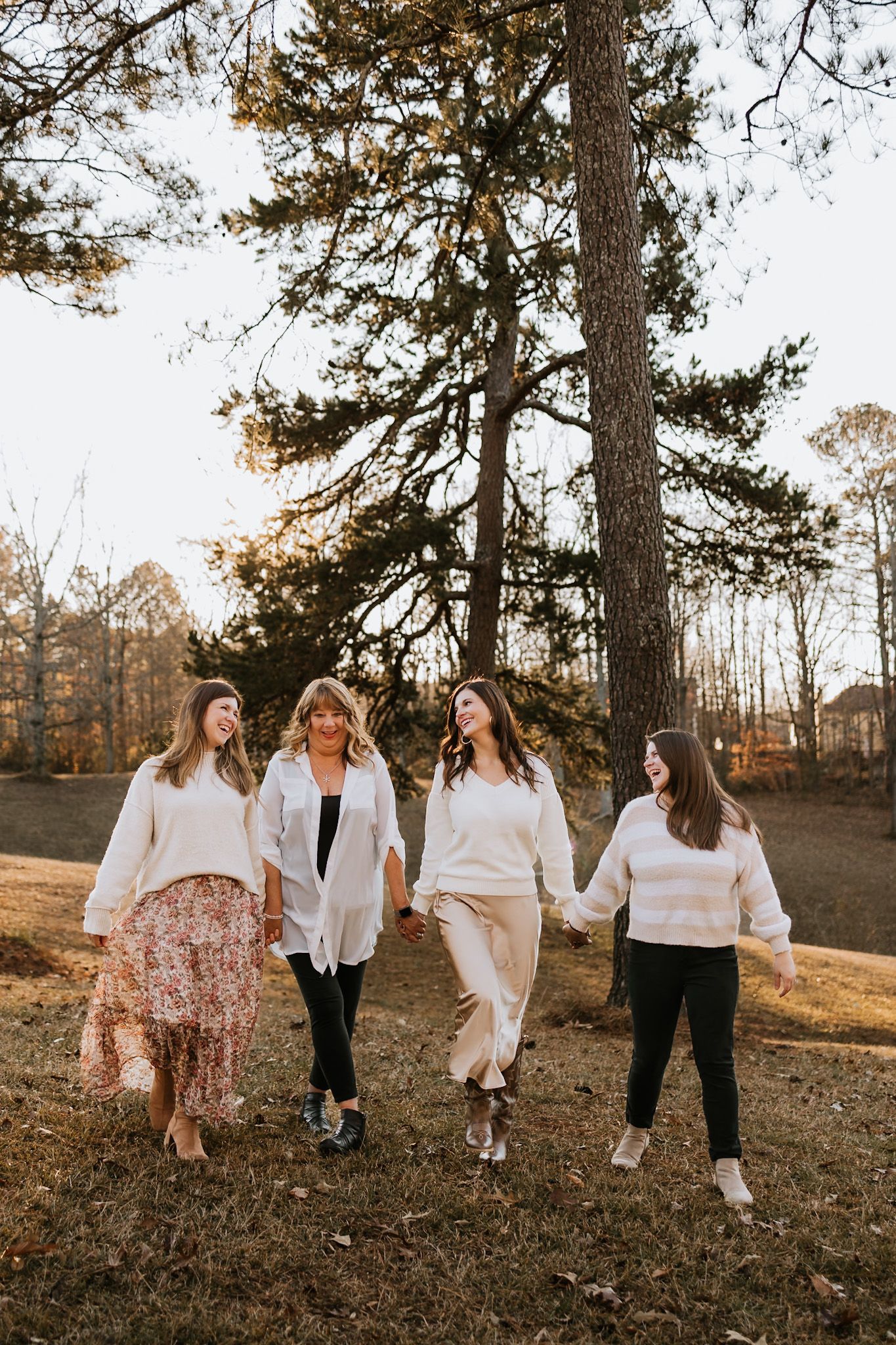 mom with 3 grown daughter holding hands, walking and laughing