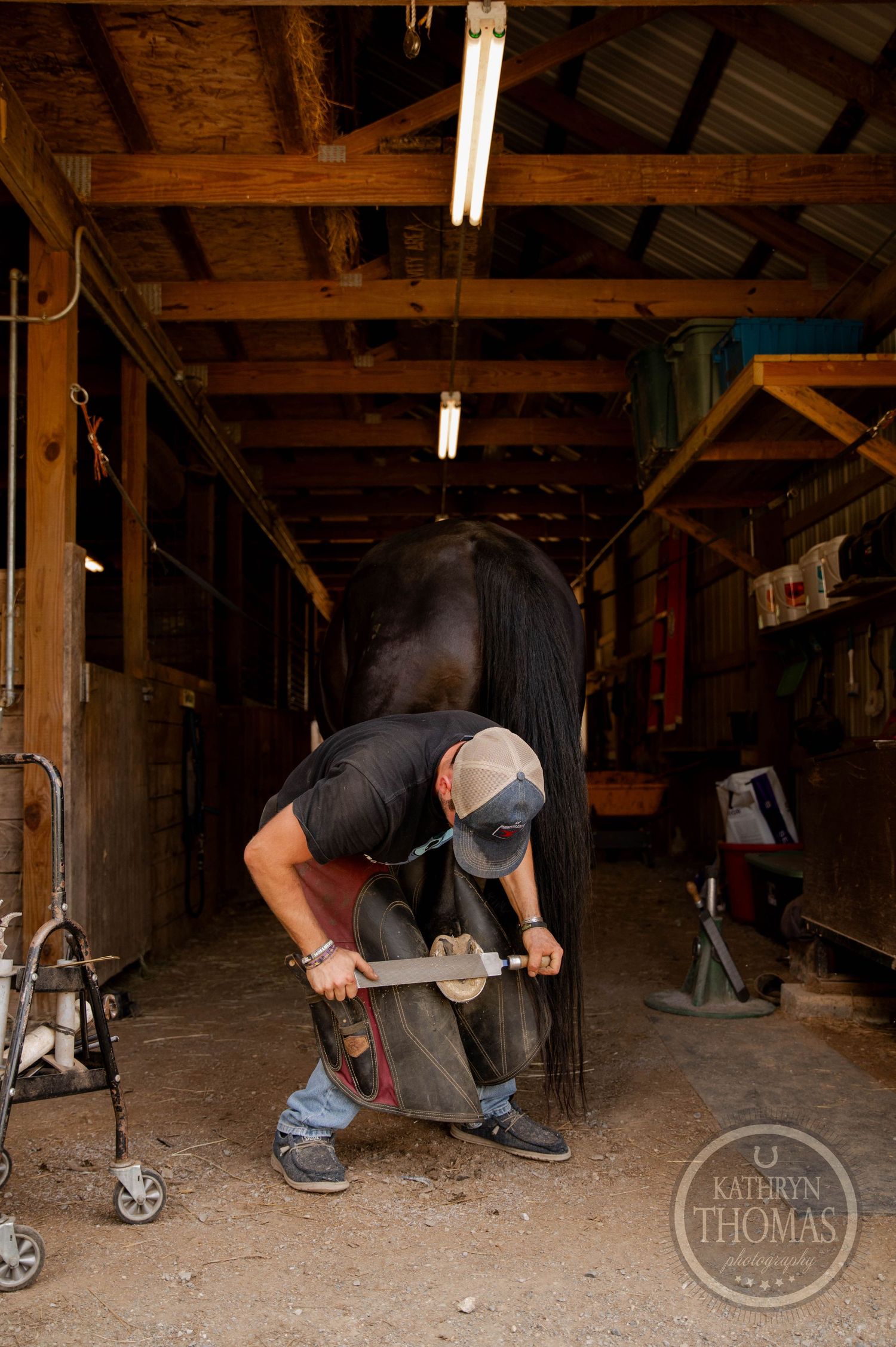 A blacksmith works diligently in a dimly lit wooden workshop with fluorescent lights overhead.