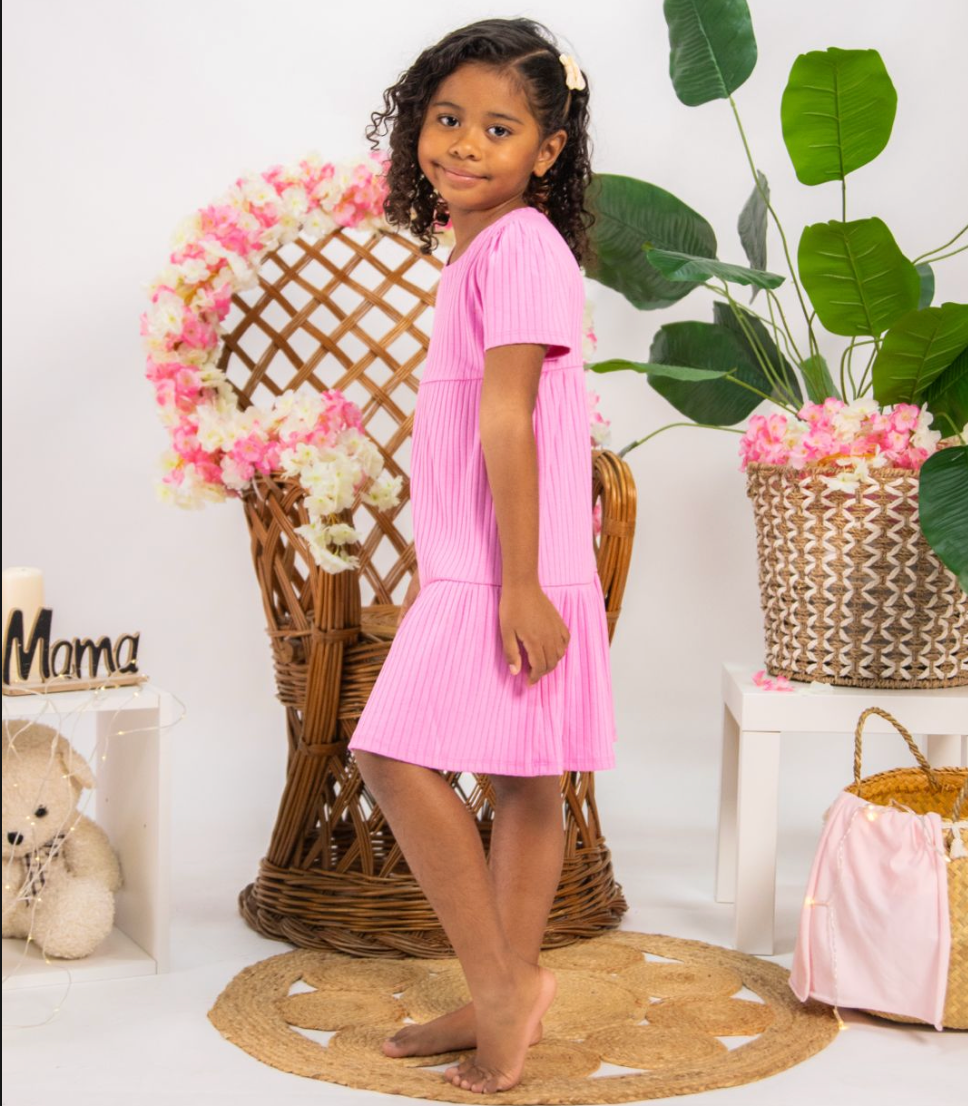 Pink dress photoshoot with decorative wicker basket and green plant accents.