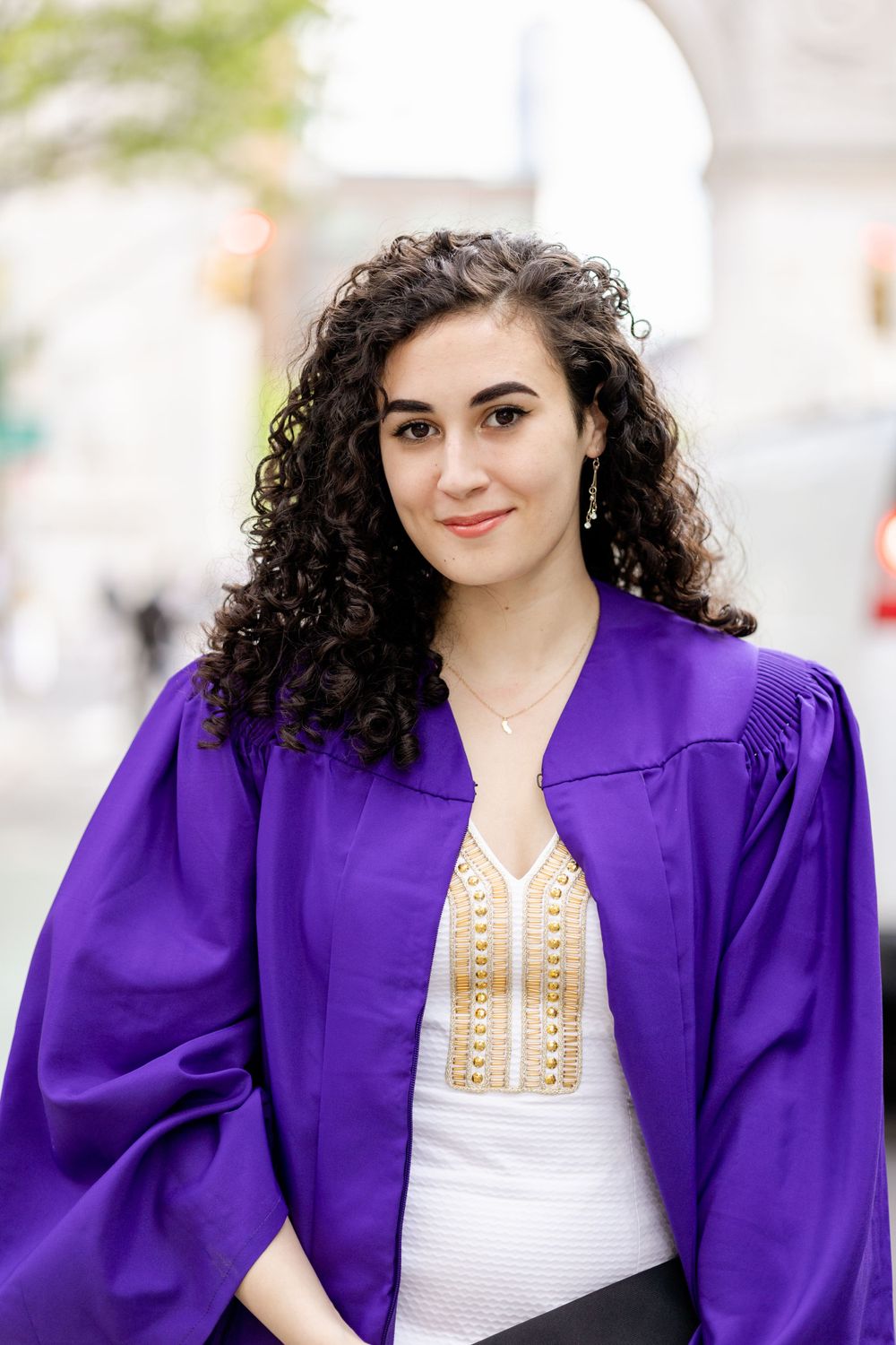 Close-up portrait of graduate in purple academic regalia.