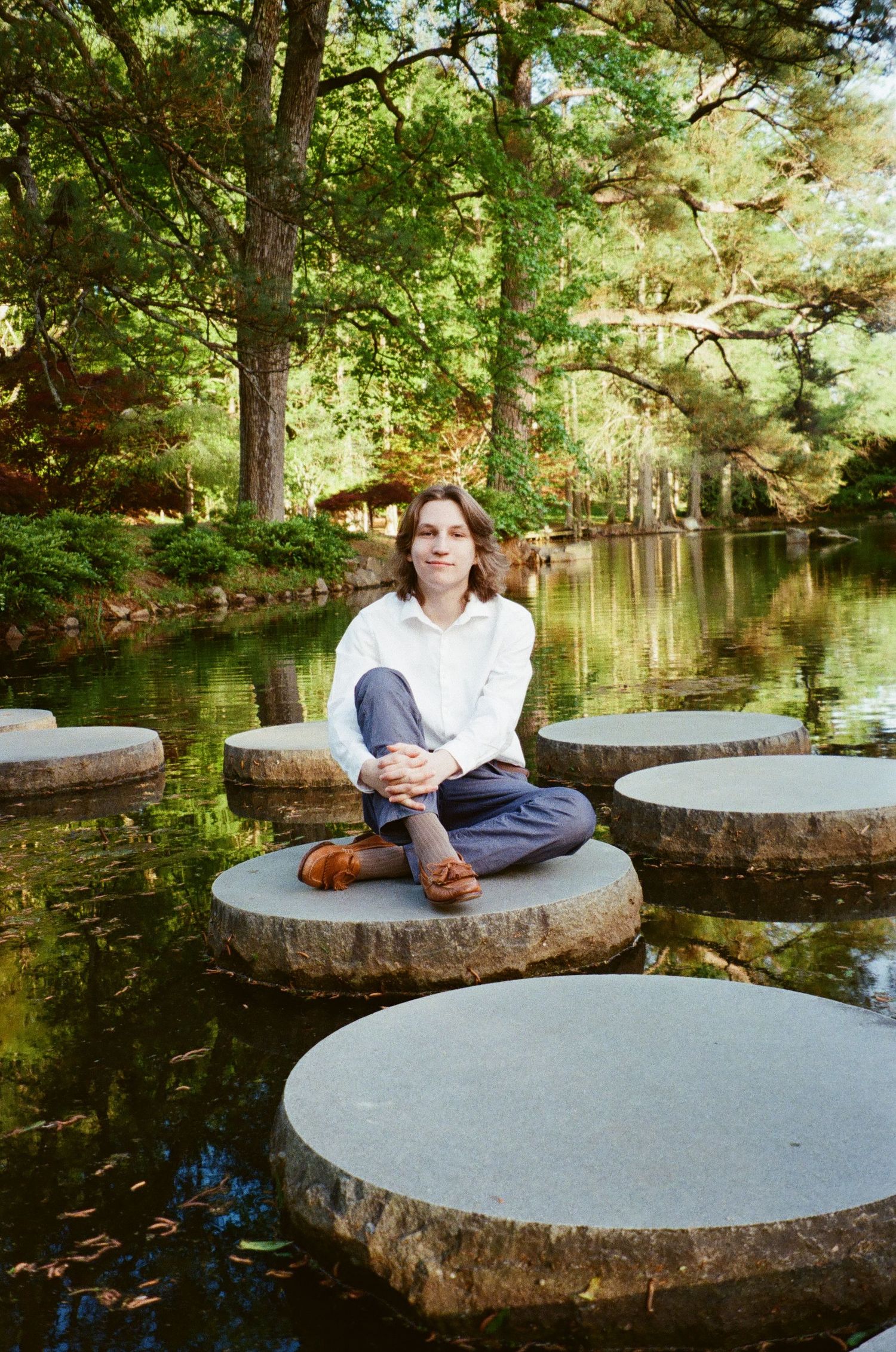 A series of circular stepping stones over a tranquil pond create a peaceful path through a lush garden setting.