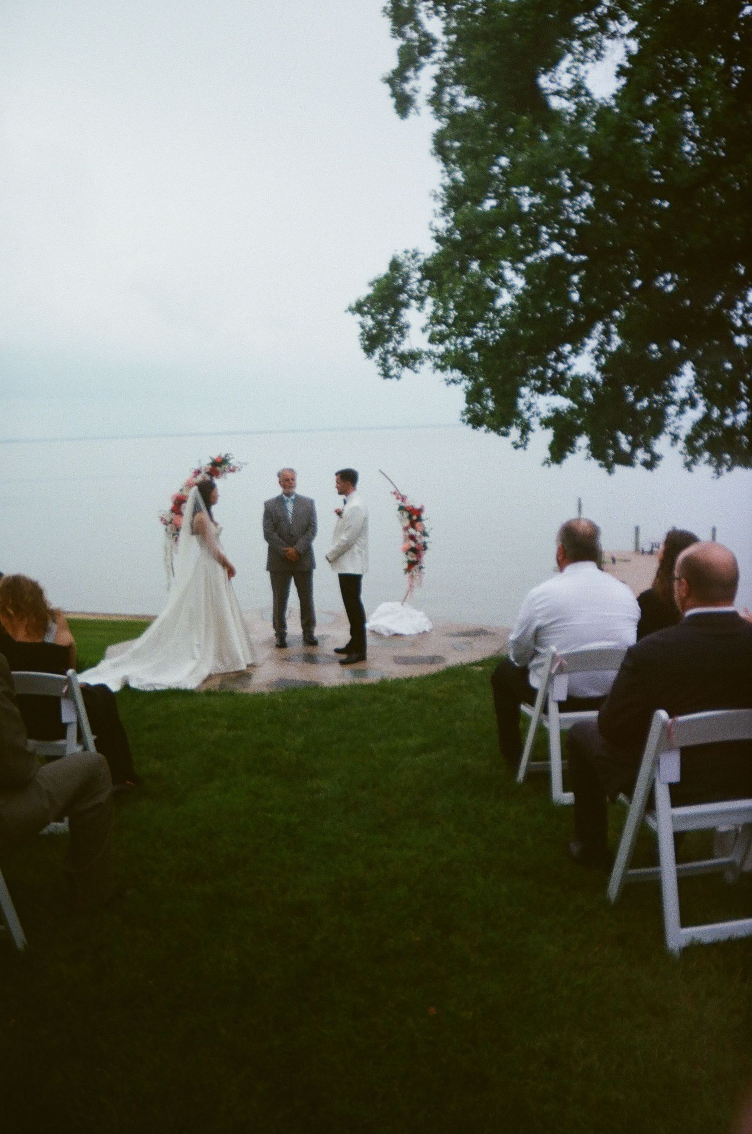 Outdoor wedding ceremony set up on a grassy hilltop overlooking a scenic waterfront view.